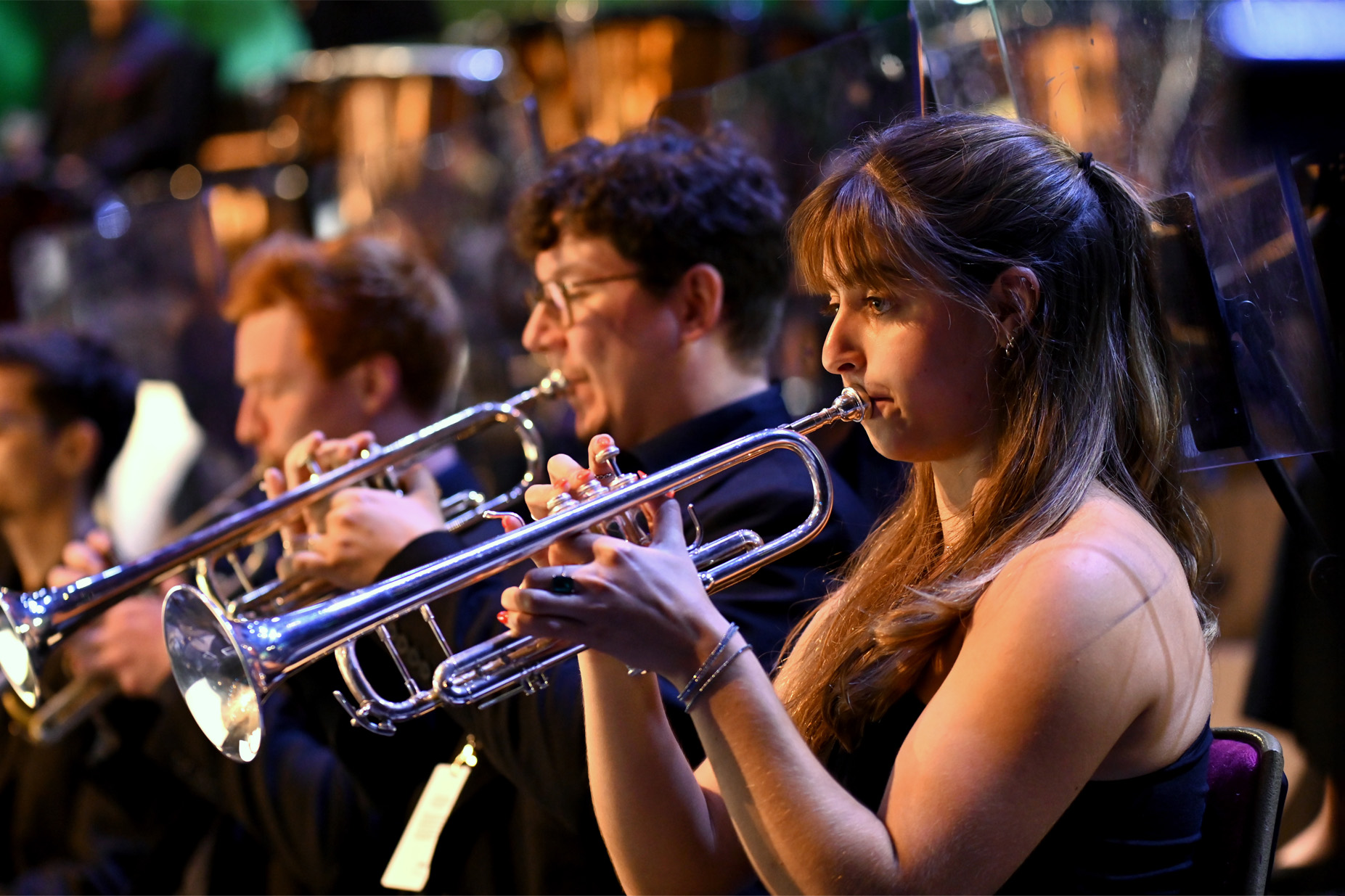 Female student performing on the trumpet in an orchestra performance, with other brass performers, in the RCM Symphony Orchestra at the BBC Proms 2024.